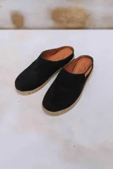 Zuecos de diseño clásico con puntera cerrada y calce práctico, confeccionados en gamuza negra con suela de goma marrón clara texturizada y plantilla interior de cuero con grabado de la marca.