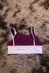 Top deportivo de entrenamiento con doble capa, color blanco exterior y borgoña interior. Presenta un corte de tirantes anchos y el logo "Hermod" en cursiva color borgoña en el pecho.