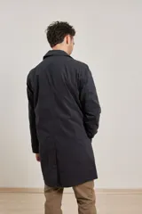 Gabardina color beige de algodón, con cuello clásico, cierre frontal con botones, dos bolsillos de ribete delanteros, bolsillo interior con botón y abertura posterior en el bajo.