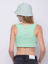 Top blanco de tela texturada, sin mangas y con cuello redondo. Cuenta con cuatro botones y terminación en curva en la parte delantera.