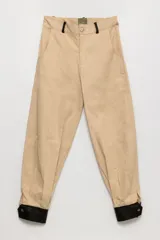 Pantalón bombacha de campo color beige, de gabardina, con corte holgado y puños negros con botones.