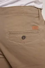 Pantalón de vestir verde oliva, de corte slim fit, sin pinzas, con bolsillos laterales y traseros. Se ajusta a la cintura con cinturón de cuero marrón.