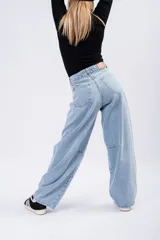 Jean de tiro alto con corte barrel leg, estilo globo, confeccionado en denim de tono azul claro. Presenta costuras reforzadas en la zona de las rodillas y un diseño de pierna ancha que se estrecha sutilmente hacia el tobillo.
