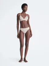Soutien triangular de encaje color beige, sin aro ni relleno, con breteles regulables y banda elastizada con logo Calvin Klein.