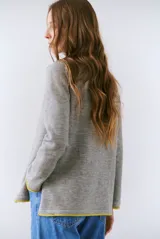 Buzo de tejido de punto color beige, con corte relajado, cuello redondo y mangas largas. Presenta detalles de terminaciones en color azul marino en los puños y en el ruedo inferior.