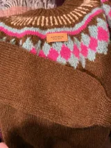 Sweater tejido a mano en mohair color beige, con cuello redondo y diseño geométrico en tonos rosa y marrón.