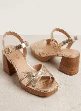 Sandalias de cuero dorado con tiras cruzadas en la parte delantera, tira ajustable con hebilla al tobillo, plataforma y taco ancho efecto madera.