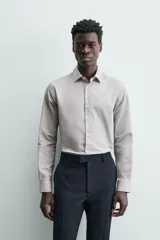 Camisa de manga larga para hombre, color gris claro con micro-estampado de cuadros sutiles. Presenta cuello italiano y cierre frontal de botonadura.