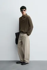 Polo de punto color marrón oscuro, de calce regular, con cuello solapa y abertura frontal en V. Presenta tejido con trencitas verticales.