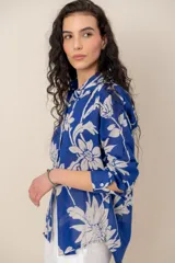 Camisa azul con estampado floral en tono blanco, de manga larga, cuello camisero y cierre frontal de botones.