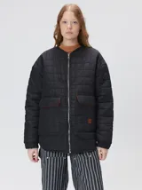 Campera reversible capitoneada con cierre frontal. Un lado es de color negro y el otro es de color beige, ambos con diseño acolchado. Cuenta con cuello redondo, mangas largas y bolsillos laterales.