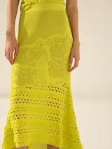 Pollera larga color amarillo, de tejido calado con diseño floral y terminación irregular con flecos.
