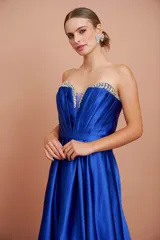 Vestido largo de fiesta color azul eléctrico, strapless, con escote corazón y detalle de piedras brillantes en el borde superior. Tiene corte imperio con falda amplia y plisada.