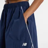 Pollera midi New Balance de tejido ripstop color azul marino, con cintura elástica, bolsillos laterales y detalles de líneas blancas en contraste. Presenta el logo de la marca en la parte inferior.