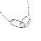 Collar plateado con cadena de eslabones pequeños y dije central formado por dos eslabones rectangulares entrelazados.