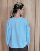 Camisa de manga larga con diseño de rayas verticales y bordados sutiles. Presenta cuello redondo, cierre frontal con botones y mangas abullonadas con volados en los hombros.