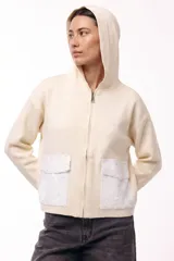Campera con capucha de corte relajado, color crema, con cierre frontal y dos bolsillos frontales con apliques de lentejuelas blancas.