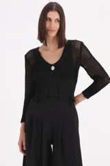 Saco corto de tejido de punto con acabado en lurex, de manga larga y escote en V con cierre de un solo botón frontal. Presenta una textura calada en las mangas y el cuerpo.