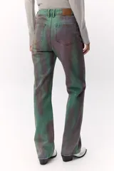 Pantalón de jean de tiro medio con estampado abstracto en tonos verdes y violetas.