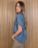 Camisa de denim liviano color azul, de mangas cortas amplias y corte oversize. Presenta cuello camisero clásico y cierre frontal con botones.