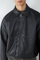 Campera de efecto cuero con cuello camisero, cierre frontal con cremallera y bolsillos laterales amplios. Presenta un diseño de corte recto y acabado liso.