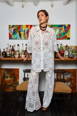 Camisa blanca de tela calada con círculos, corte holgado y mangas cortas.