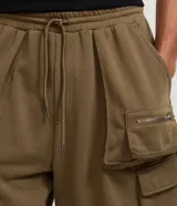Bermuda cargo para hombre de color verde militar, confeccionada en algodón con felpa y poliéster. Cuenta con múltiples bolsillos cargo laterales y cierre de cremallera.