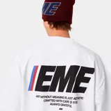 Camiseta blanca de corte cuadrado con estampado en la espalda que incluye la palabra "EME" en letras grandes con detalles en rojo y azul, y una frase debajo.