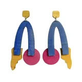 Aros colgantes de madera de tilo pintados con acuarela y barniz transparente, con diseño geométrico en colores amarillo, azul y rosa.