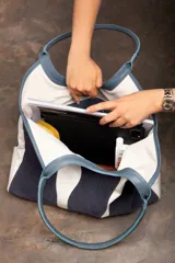 Bolso tipo tote de tela color crudo con detalles de cuero marrón en las asas y la base.