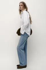 Jeans de tiro alto con diseño de cinco bolsillos, pernera recta y corte largo. Presenta cierre frontal con cremallera y botón metálico.