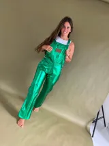 Enterito de cuero verde esmeralda con corte recto y bolsillos laterales. Presenta tirantes regulables y cierre con botones metálicos a los costados.