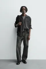 Camisa de manga larga color negro, confeccionada en tejido fluido con mezcla de viscosa. Presenta cuello bowling, bolsillo de vivo en el pecho y efecto lavado.