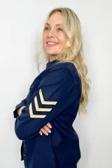 Sobre camisa azul marino de algodón con cierre de botones, dos bolsillos frontales con solapa y detalle de galones en color beige en las mangas.