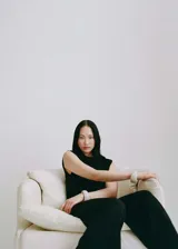 Mono largo negro de poliéster con escote drapeado, cuello Perkins, diseño recto, sin mangas, detalle fruncido en la cintura y cierre de cremallera en la parte posterior.