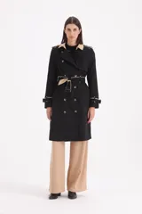Piloto 7/8 de corte trench, color negro con detalles en beige en cuello, solapas y puños. Presenta cierre cruzado con botones, cinturón con hebilla y charreteras en los hombros.
