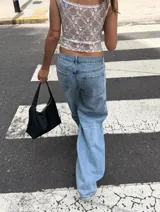 Corset de encaje negro con diseño floral, copas estructuradas y cierre frontal con botones a presión. Presenta breteles anchos de encaje y espalda con diseño de red.