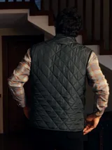 Chaleco acolchado de diseño capitoneado con cierre frontal de botones a presión y bolsillos delanteros con solapa. Presenta un cuello alto y un corte clásico.