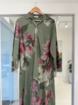 Vestido midi verde militar con estampado floral en tonos rosados y blancos, cuello camisero y cierre frontal parcial con botones.