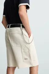 Bermuda relaxed fit confeccionada en tejido de algodón con efecto lavado. Presenta un diseño de cinco bolsillos, bolsillo multifunción en la pernera y tira lateral de estilo carpintero. Cuenta con cierre frontal con cremallera y botón.