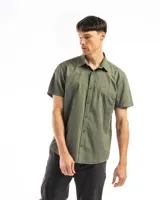 Camisa de manga corta color verde militar, confeccionada en algodón, con cuello clásico y un bolsillo de parche en el lado izquierdo del pecho.