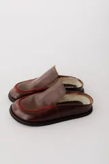 Zueco de cuero color marrón oscuro, con costuras decorativas en hilo rojo en el empeine y suela plana de goma.