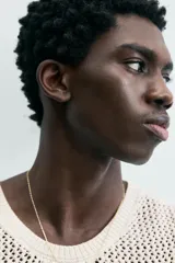 Chaleco de punto color blanco roto, con cuello redondo y sisa, confeccionado en tejido calado de estructura abierta y acabado en rib.