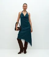 Pollera midi de satén color verde petróleo, con corte asimétrico y detalle de encaje aplicado en el ruedo. Presenta una cintura estructurada y una caída fluida.