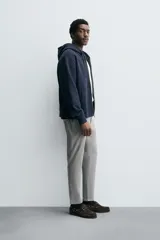 Pantalón de corte slim fit confeccionado en tejido elástico, con cintura elástica, cierre frontal con cremallera y botón, bolsillos laterales y bolsillos traseros de vivo.