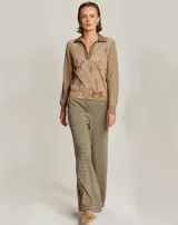 Polo de punto color beige con estampado de motivos ecuestres en tonos marrones. Tiene cuello clásico, tapeta frontal y mangas largas.