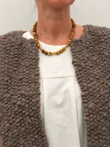 Collar Ound modelo Guayabo, elaborado con cuentas esféricas de piedra en tonos verdosos y marrones, intercaladas con separadores cilíndricos dorados. Cierre de mosquetón dorado.
