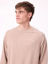 Sweater de cuello redondo y manga larga con diseño de hombros raglán, confeccionado en tejido de punto acanalado con efecto lavado. Presenta un pequeño logo bordado en el pecho.