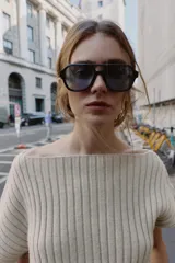 Top de punto rib color beige claro, con escote barco y mangas cortas asimétricas. Se ajusta a la cintura con un cinturón fino negro con hebilla metálica.