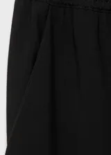 Pantalón fluido de color negro con cintura elástica y cordón ajustable. Presenta diseño recto y bolsillos laterales.
